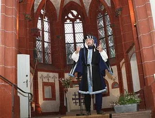 Mann in historischem Kostüm in einer Kirche.