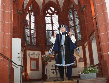 Mann in historischem Kostüm in einer Kirche.