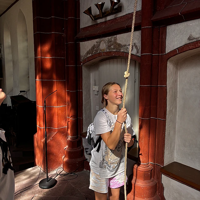 Mädchen läutet Glocke in Kirchturm.