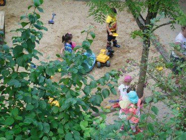 Kinder spielen in einem großen Sandkasten.