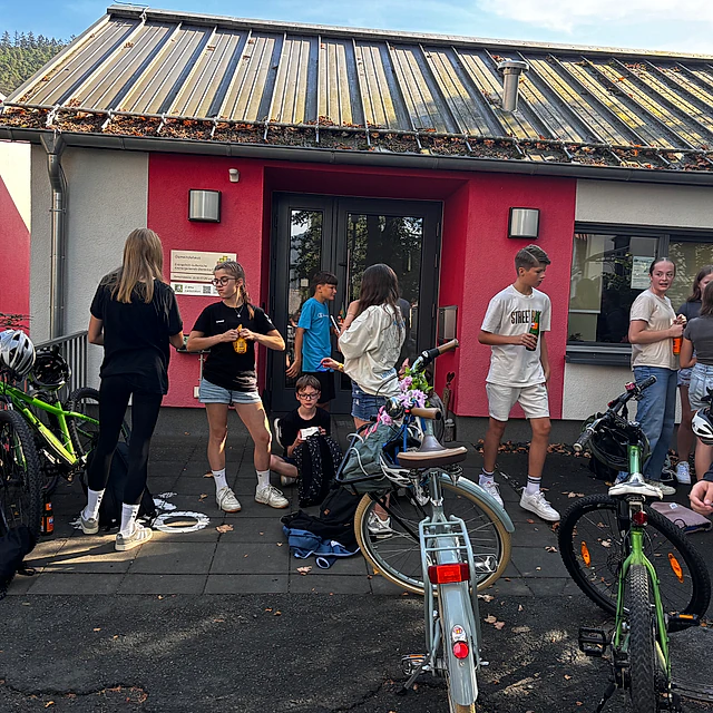 Jugendliche mit Fahrrädern vor einem Gebäude.