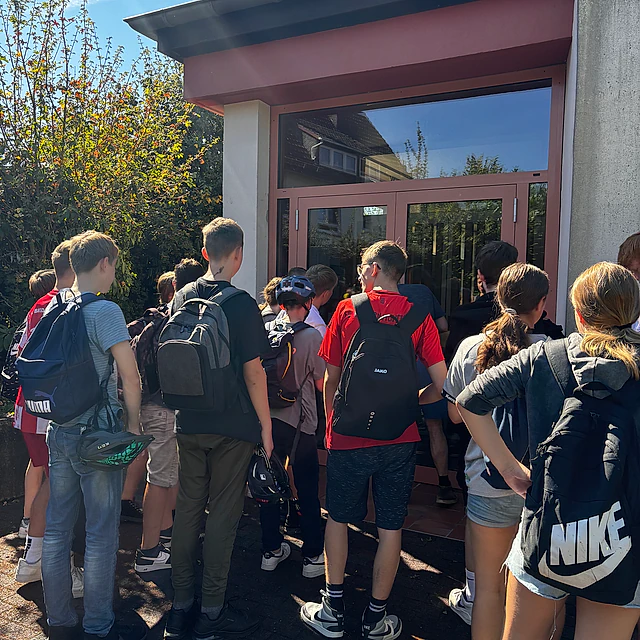 Jugendliche stehen vor einem Gebäude.