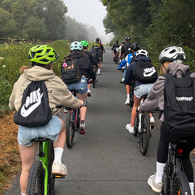 Gruppe radelt auf nebliger Straße.