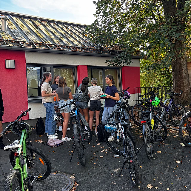 Menschen mit Fahrrädern vor einem Gebäude.
