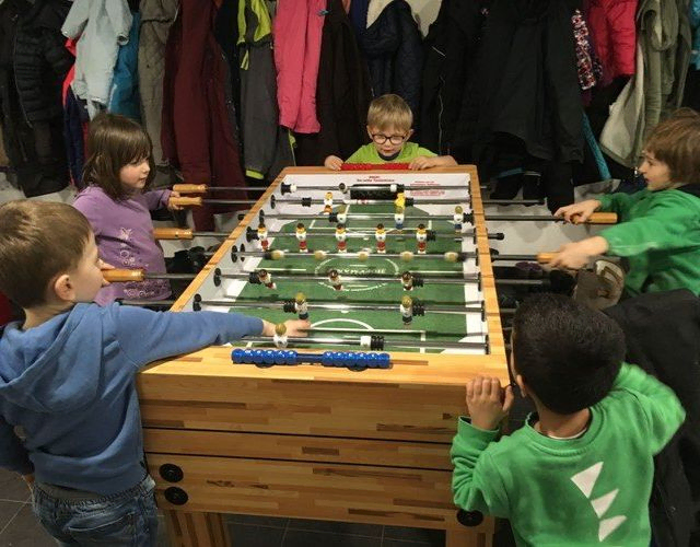 Kinder spielen Tischfußball.