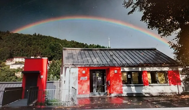 Regenbogen über einem roten und weißen Gebäude.