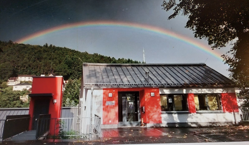Regenbogen über einem roten und weißen Gebäude.