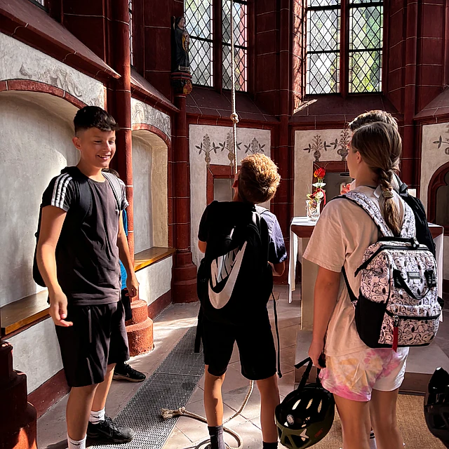 Jugendliche in Kirchturm mit Glocken.