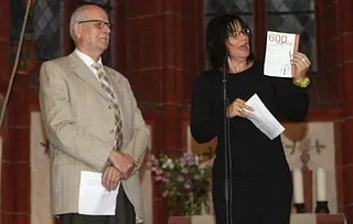 Frau hält Buch vor Mann in Kirche.