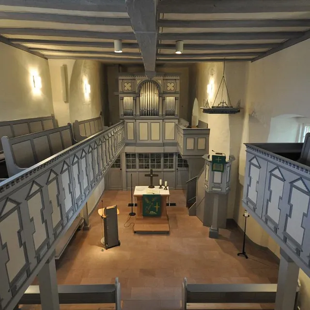 Kircheninnenraum mit Orgel und Bänken.