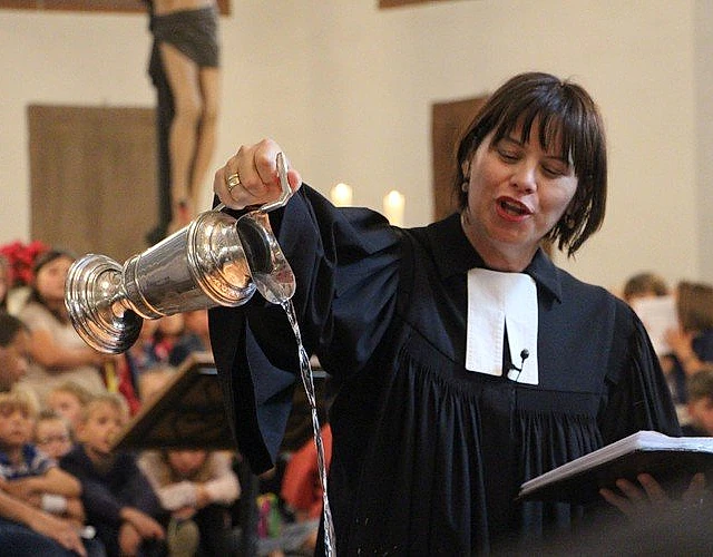 Pastorin bei Taufe mit Taufkanne.