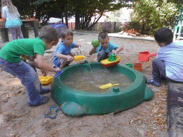 Kinder spielen mit Wasser und Sand.