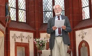 Älterer Mann spricht in einer Kirche.