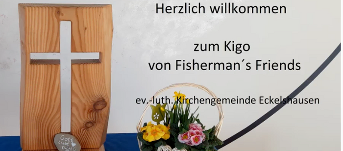 Willkommensschild für Kigo mit Holzkreuz und Blumenkorb.
