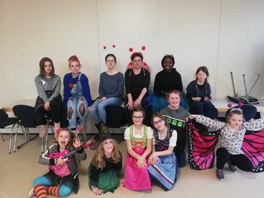 Gruppe von Mädchen in Kostümen und Alltagskleidung.