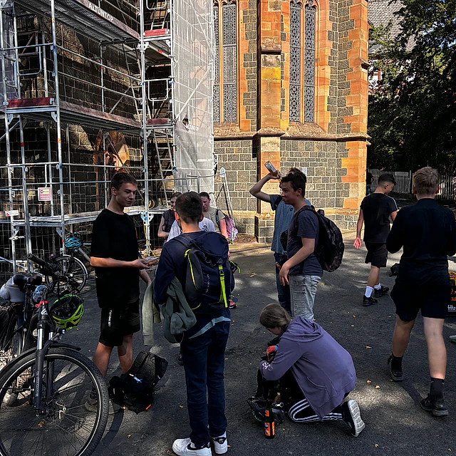 Jugendliche mit Fahrrädern vor einer Kirche.