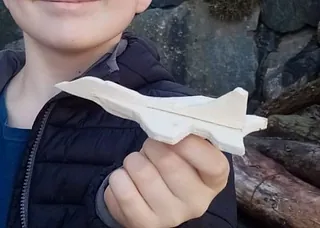 Kind hält Papierflugzeug.