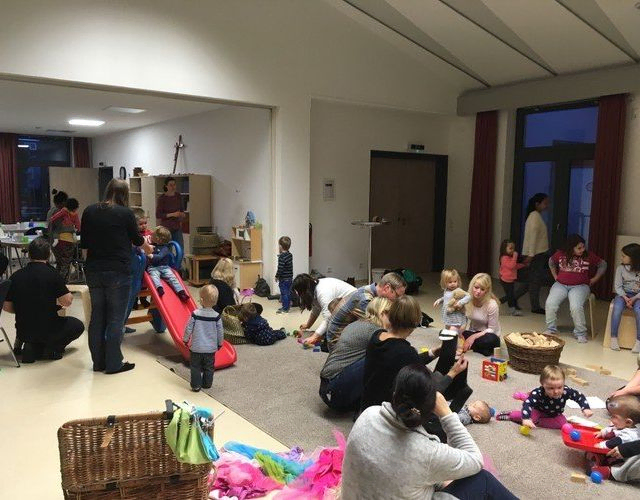Erwachsene und Kinder spielen in einem Raum.