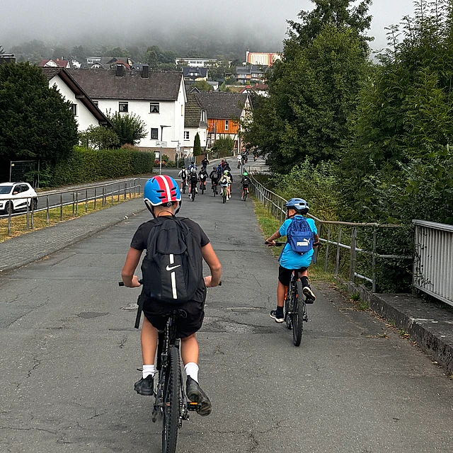 Person radelt bergab auf Straße.