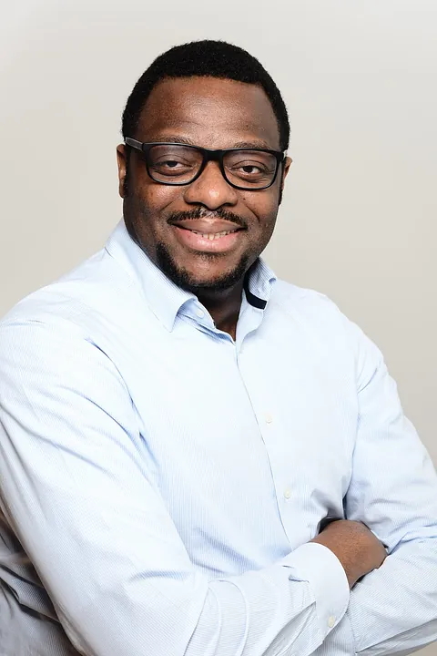 Porträt eines lächelnden Mannes mit Brille.