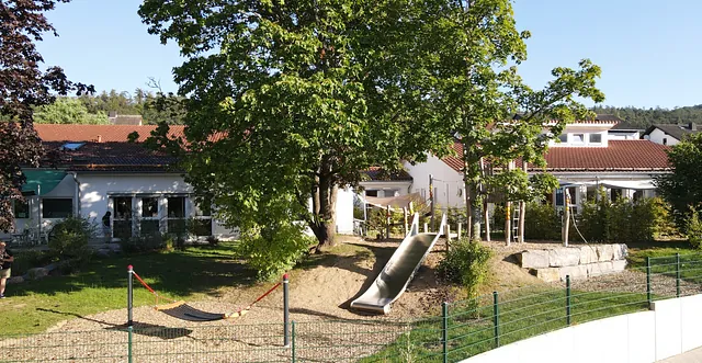 Kinderspielplatz mit Rutsche und Gebäuden.