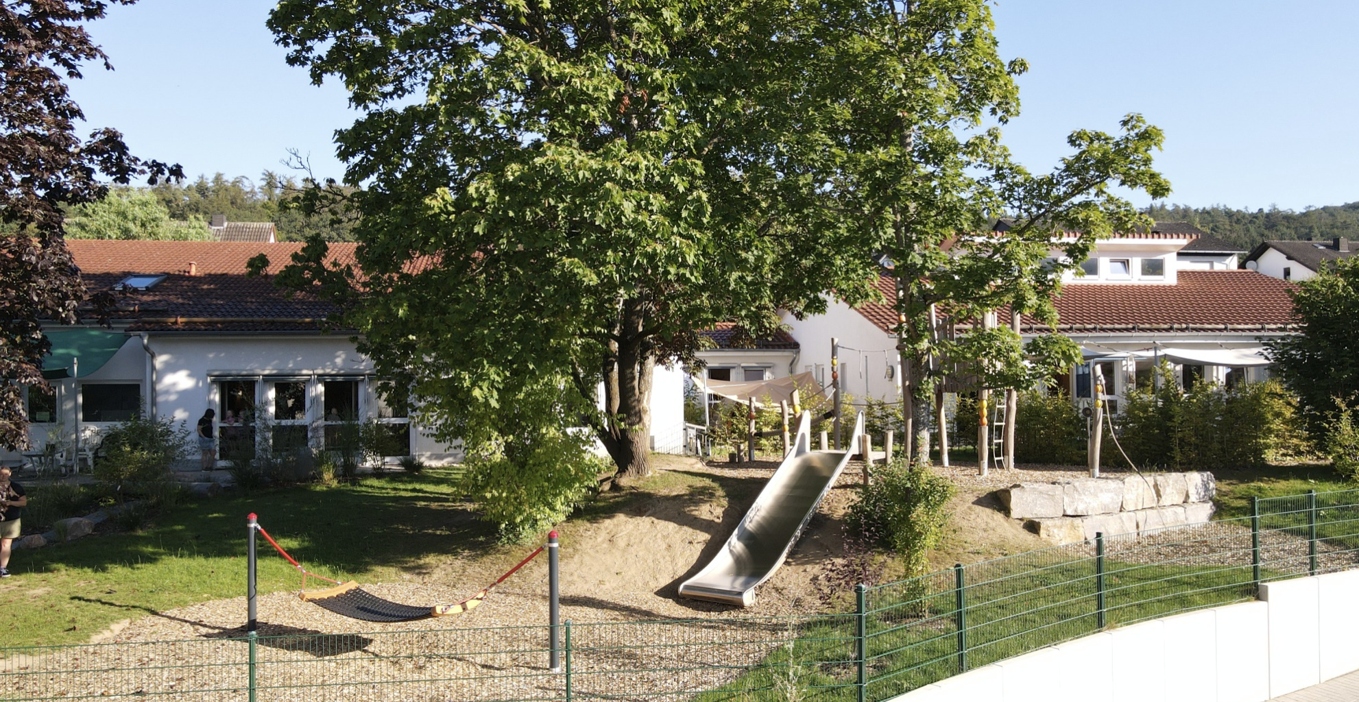 Kinderspielplatz mit Rutsche und Gebäuden.