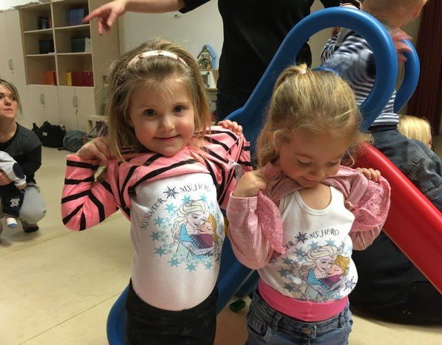 Zwei Kleinkinder lächeln in die Kamera.