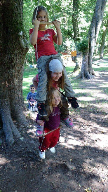 Drei Kinder spielen auf einer Schaukel.