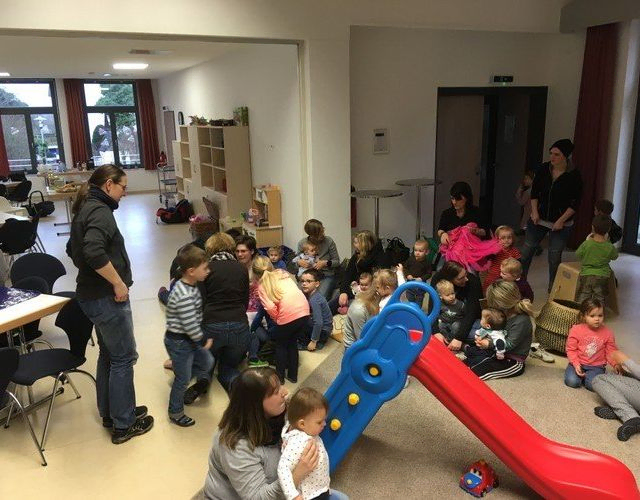 Gruppe von Kindern und Erwachsenen in einem Spielzimmer.