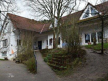 Weißes Gebäude mit rotem Dach und Rampe.