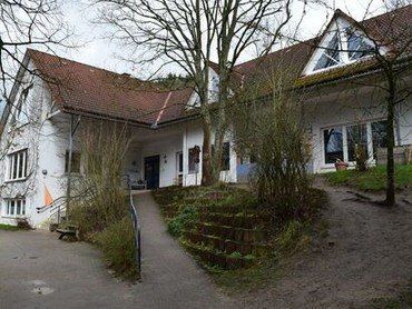 Weißes Gebäude mit rotem Dach und Rampe.